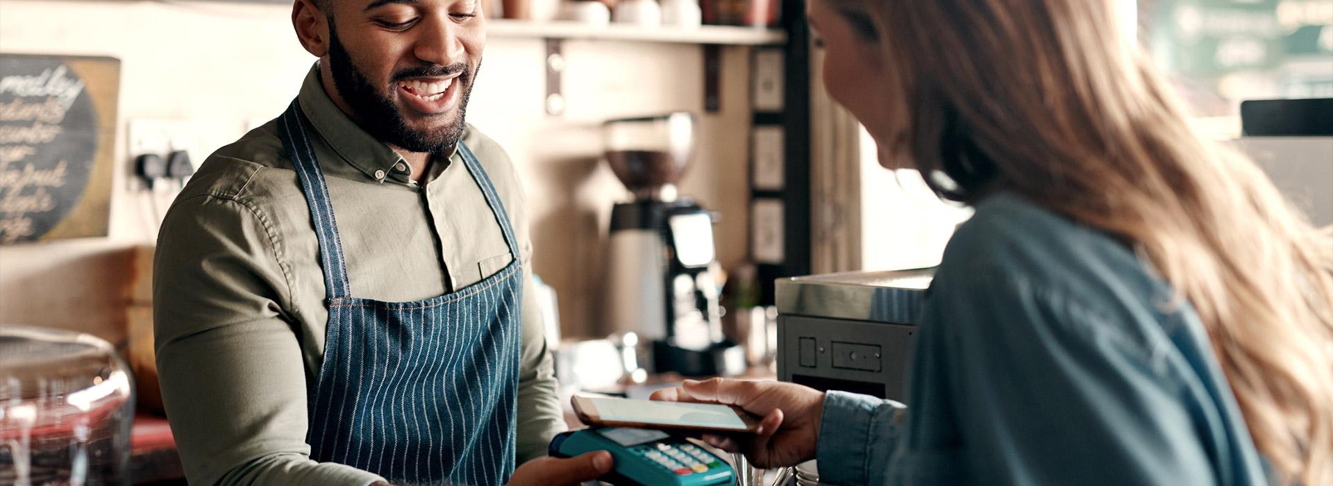 Woman holding credit card over credit card processor machine (male merchant holding the processor)
