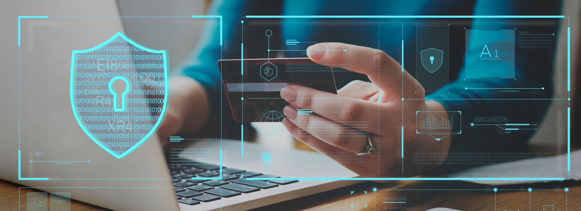 guy holding credit card in front of laptop