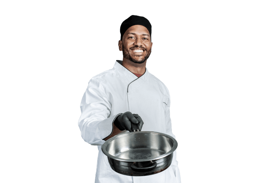 Smiling chef in white uniform and black cap holding empty stainless steel pan against white background.