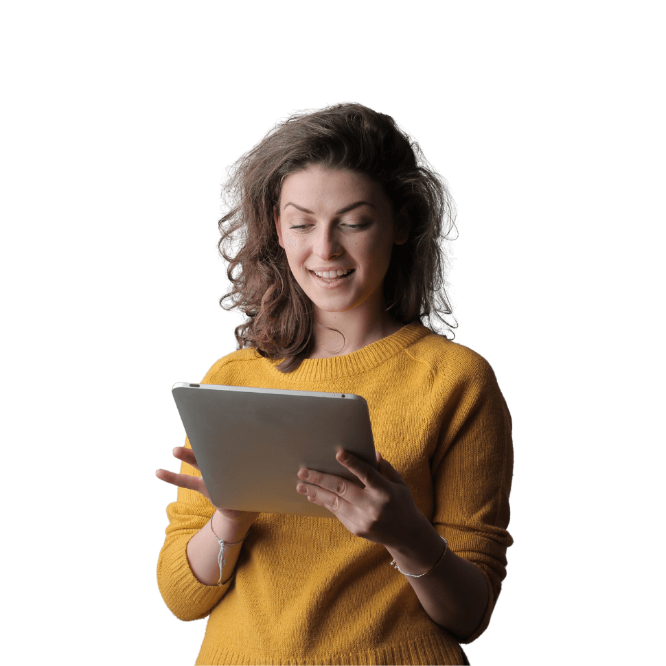 Woman in yellow sweater smiling while holding and looking at a tablet device against white background.
